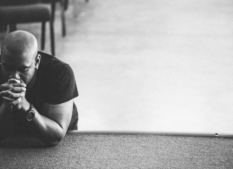 Black man kneeling to pray